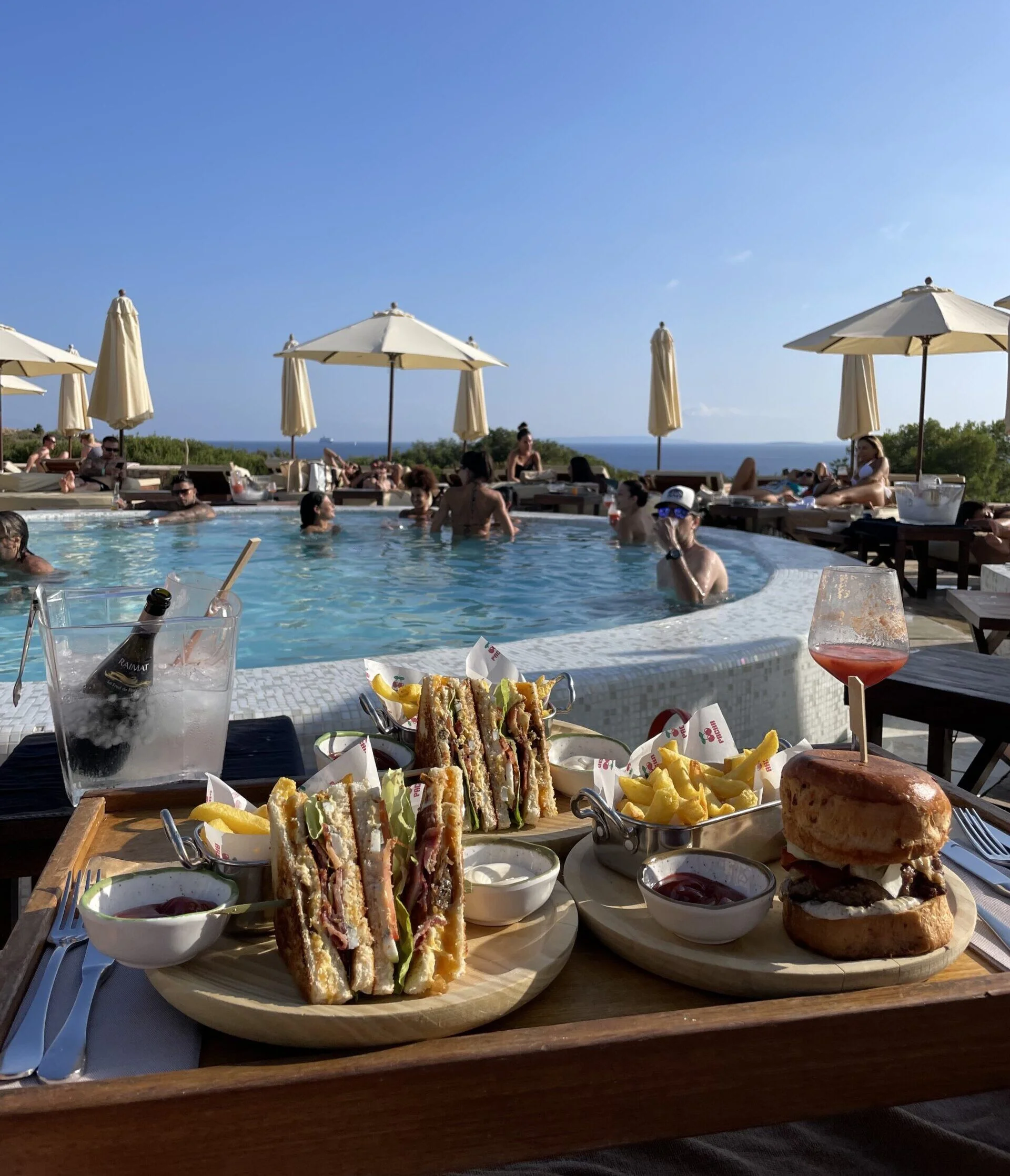 Hamburger met frieten en gegrilde sandwiches aan een zwembad in Ibiza